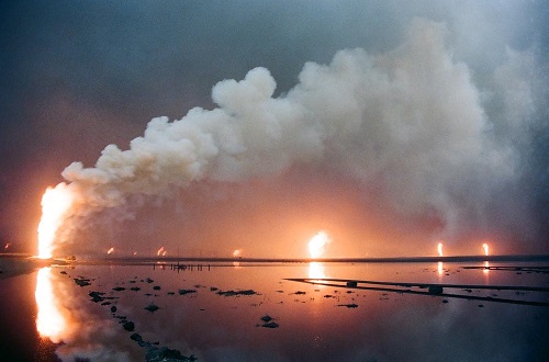 Burning oil wells behind lake of oil, Kuwait, 1991.